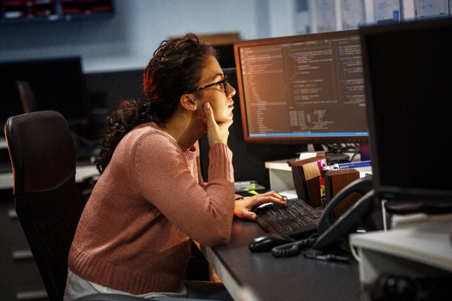 Млада жена работи като програмист в офис през нощта