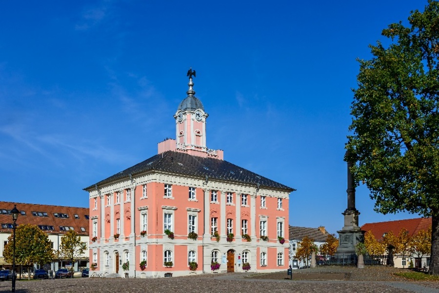 Das historische Rathaus am Templiner Marktplatz, ein dreigeschossiger Barockbau mit Putzfassade, Walmdach und einem Turm mit einem Adler auf der Spitze