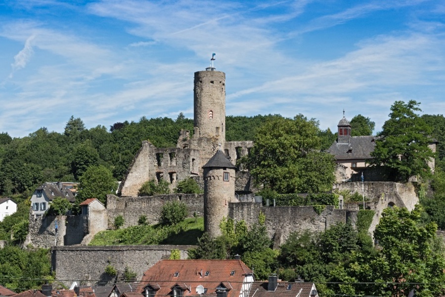 Die Burgruine in Eppstein, auf einem bewaldeten Hügel gelegen. In der Mitte ein Turm mit Flagge.