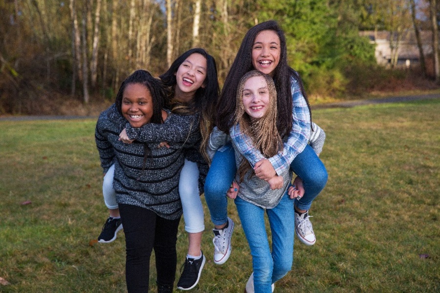  Four smiling girls of different ethnicities giving piggyback rides