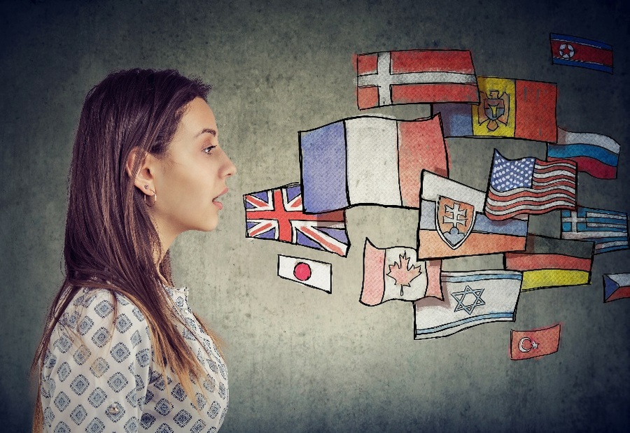  Woman seen from the side, with national flags drawn on the wall behind her as if coming out of her mouth, symbolising multilingualism