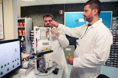 Twee wetenschappers in laboratoriumjassen werken met radioactief materiaal met behulp van een machine