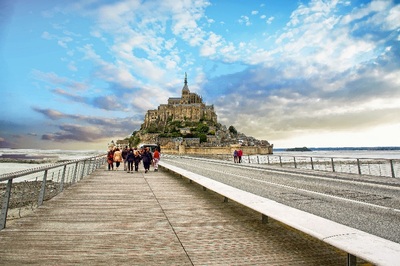 Изглед от Мон Сен Мишел с абатството и моста към него, по който вървят туристи