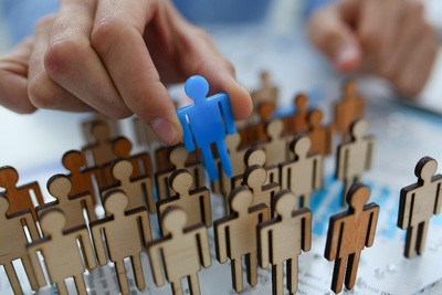 Eine Hand hält eine blaue Figur über einer Gruppe brauner Figuren