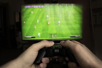 Labdarúgó-videójáték konzolját működtető kezek