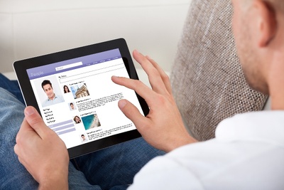 Egy kényelmes kanapén ülő férfi táblagépen böngészik az interneten